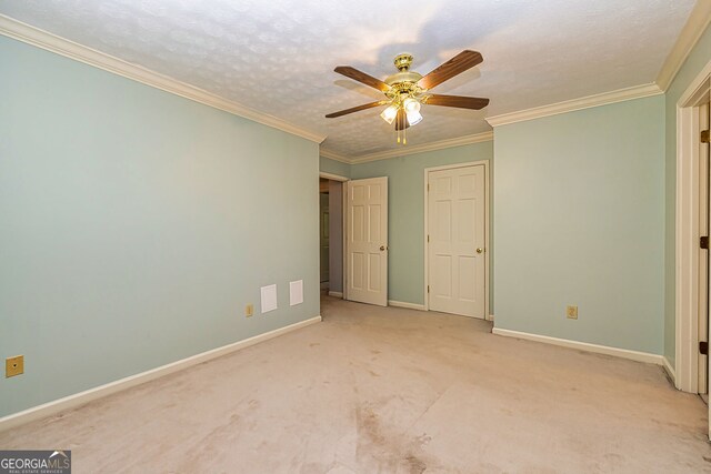 unfurnished bedroom with carpet floors, baseboards, crown molding, and ceiling fan