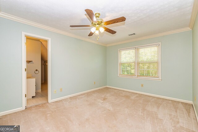 unfurnished bedroom with carpet flooring, crown molding, baseboards, a ceiling fan, and ensuite bathroom