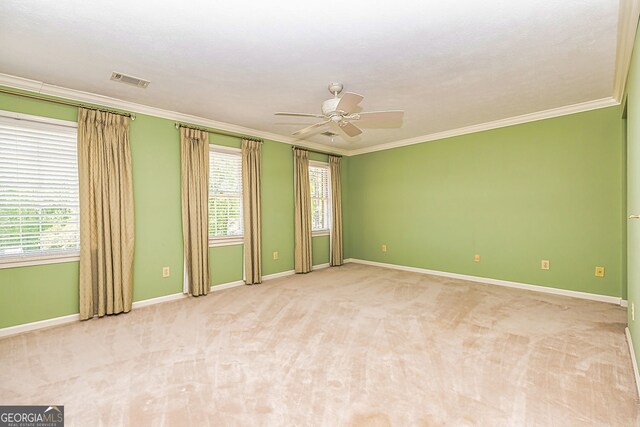 spare room featuring crown molding, healthy amount of natural light, ceiling fan, light colored carpet, and baseboards