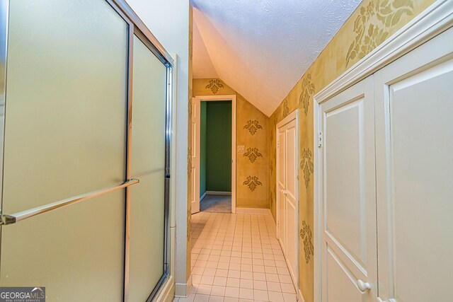 bathroom featuring lofted ceiling, tile patterned floors, and a textured ceiling