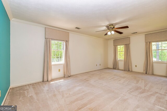 empty room with ornamental molding, a ceiling fan, light carpet, and baseboards