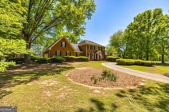 view of front of home featuring curved driveway, a front lawn, and a garage
