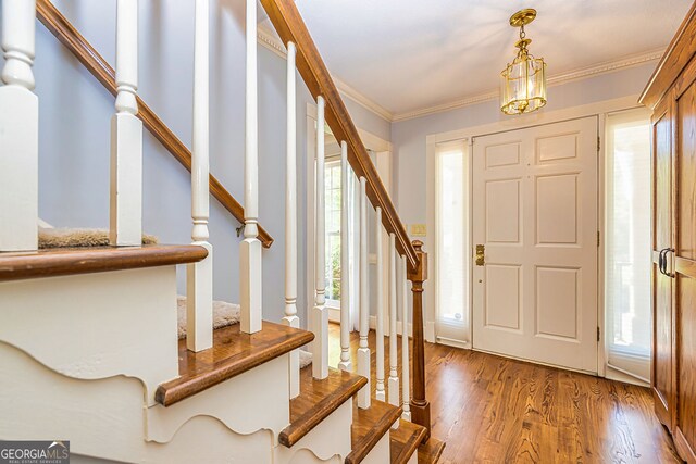 foyer entrance with stairway, ornamental molding, and wood finished floors