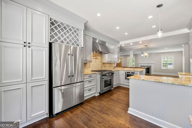 kitchen featuring appliances with stainless steel finishes, wall chimney range hood, a peninsula, recessed lighting, and dark wood-style flooring