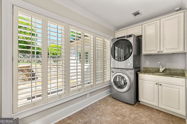 laundry room with stacked washer / dryer, cabinet space, light tile patterned floors, and ornamental molding