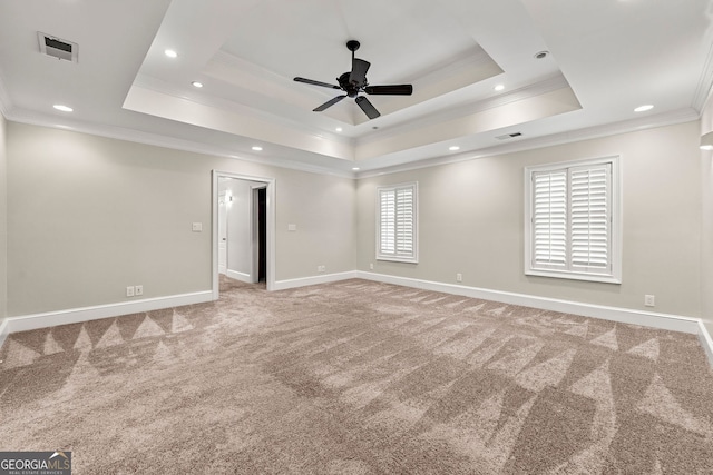 spare room featuring ornamental molding, carpet flooring, a ceiling fan, a raised ceiling, and baseboards