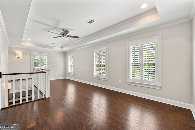 empty room featuring a tray ceiling, wood finished floors, a ceiling fan, baseboards, and ornamental molding