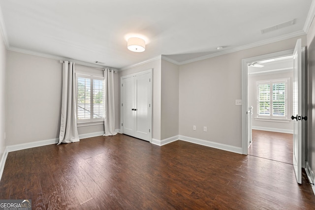 unfurnished bedroom with multiple windows, ornamental molding, dark wood finished floors, and baseboards