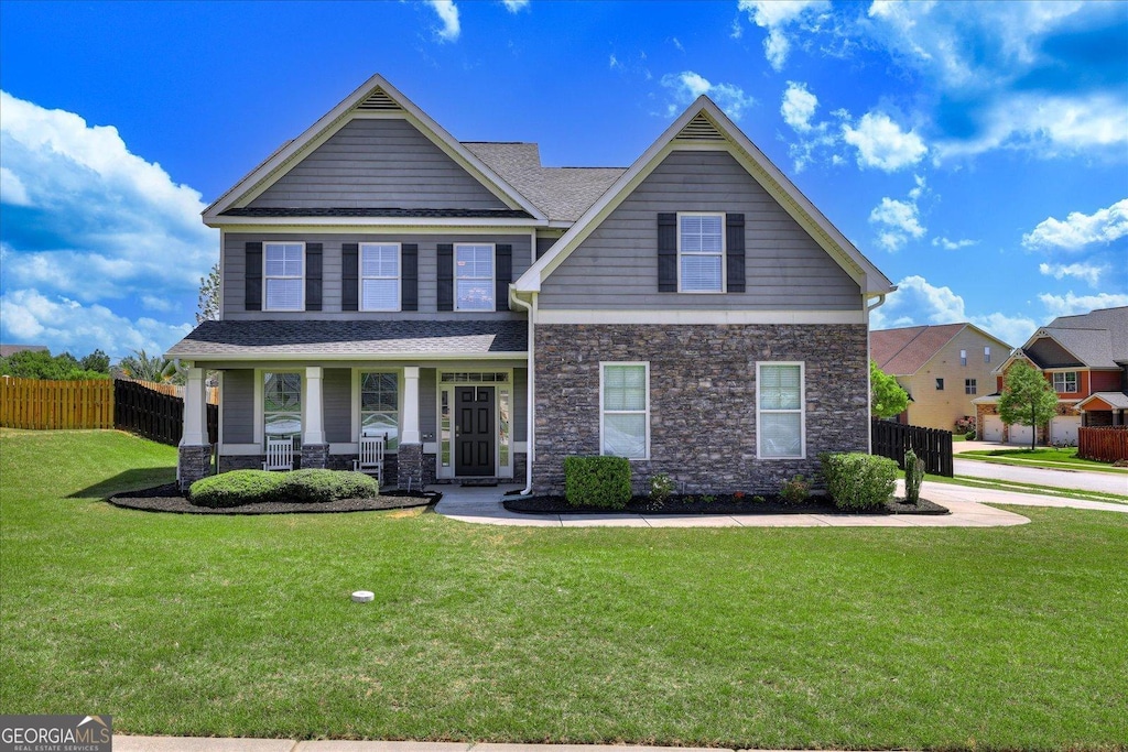 302 Clearwater Ln, Grovetown, GA 30813 - craftsman-style house with stone siding, covered porch, fence, a shingled roof, and a front yard