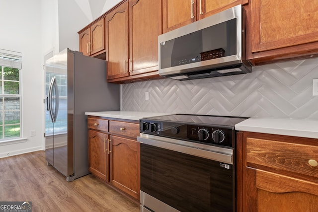 103 St Albans Way, Peachtree City, GA 30269 - kitchen featuring brown cabinetry, decorative backsplash, appliances with stainless steel finishes, and light wood-type flooring