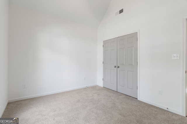 103 St Albans Way, Peachtree City, GA 30269 - unfurnished bedroom with visible vents, a closet, baseboards, high vaulted ceiling, and carpet flooring