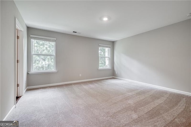 empty room featuring carpet floors, visible vents, and baseboards