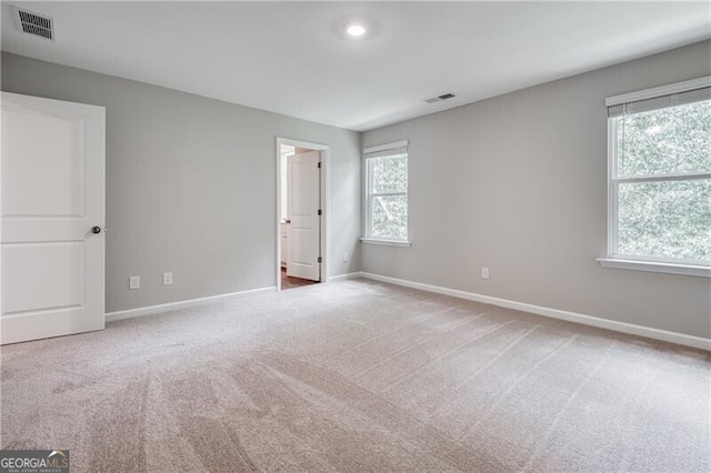 unfurnished bedroom featuring carpet floors, multiple windows, and visible vents