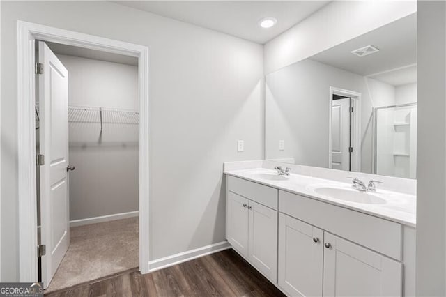 full bathroom featuring a sink, double vanity, visible vents, a spacious closet, and wood finished floors