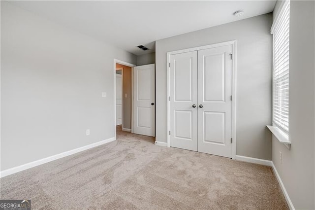 unfurnished bedroom featuring baseboards, a closet, visible vents, and carpet
