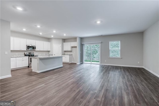 kitchen featuring dark wood finished floors, baseboards, open floor plan, and stainless steel appliances