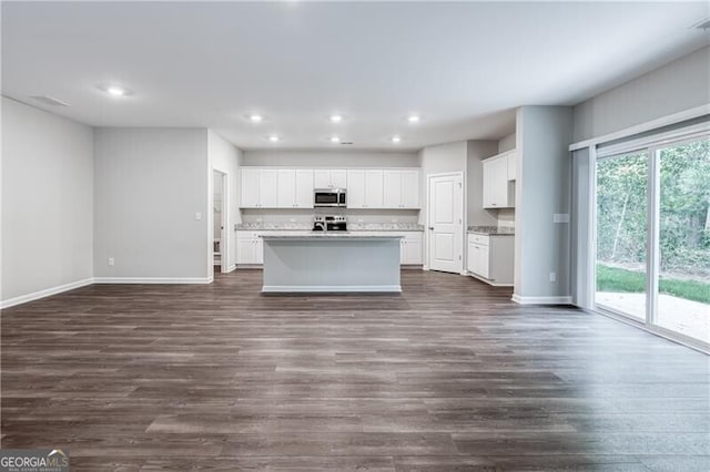kitchen featuring open floor plan, stainless steel microwave, baseboards, dark wood-style floors, and recessed lighting