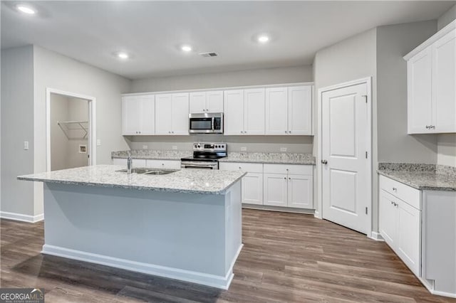 kitchen featuring a sink, stainless steel appliances, a center island with sink, white cabinets, and visible vents