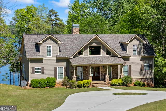 view of front of property featuring a front lawn, covered porch, roof with shingles, and central air condition unit