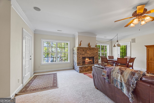 living area with visible vents, ornamental molding, carpet floors, baseboards, and ceiling fan