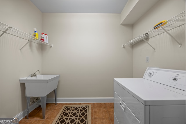 clothes washing area with light tile patterned floors, washer / dryer, laundry area, and baseboards