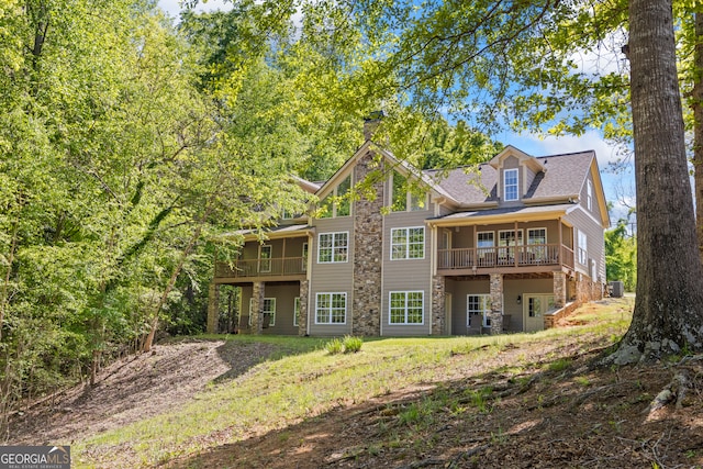 rear view of property with a wooden deck and stone siding