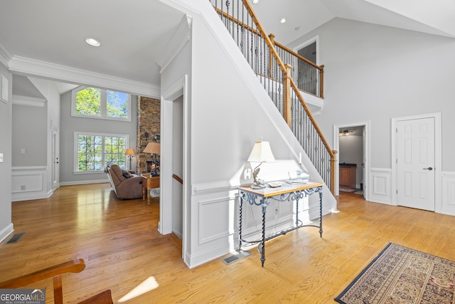 entrance foyer featuring stairway, a decorative wall, light wood-style flooring, a fireplace, and visible vents