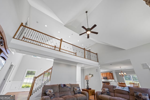 living area with high vaulted ceiling, stairway, ceiling fan with notable chandelier, light wood finished floors, and recessed lighting