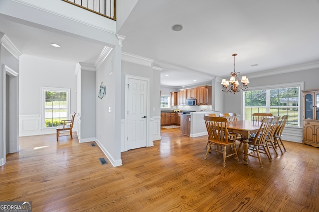 dining room with light wood-style floors, ornamental molding, and a notable chandelier