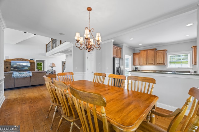 dining space with an inviting chandelier, crown molding, and light wood-type flooring