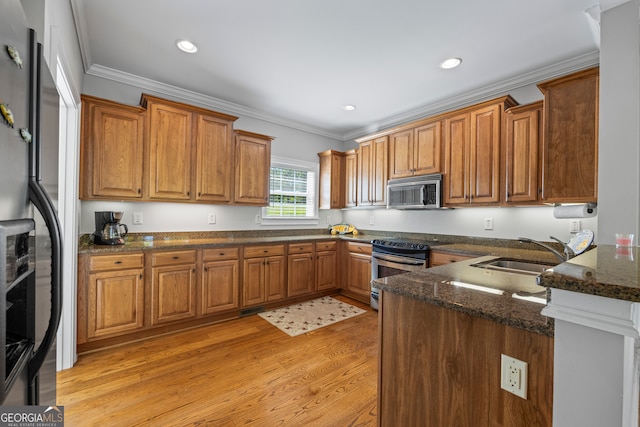 kitchen with stainless steel appliances, a sink, brown cabinets, and ornamental molding