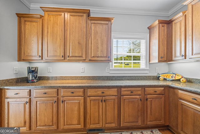 kitchen featuring brown cabinetry, visible vents, and crown molding