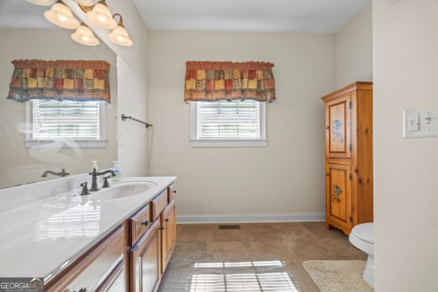 bathroom with baseboards, a healthy amount of sunlight, vanity, and visible vents