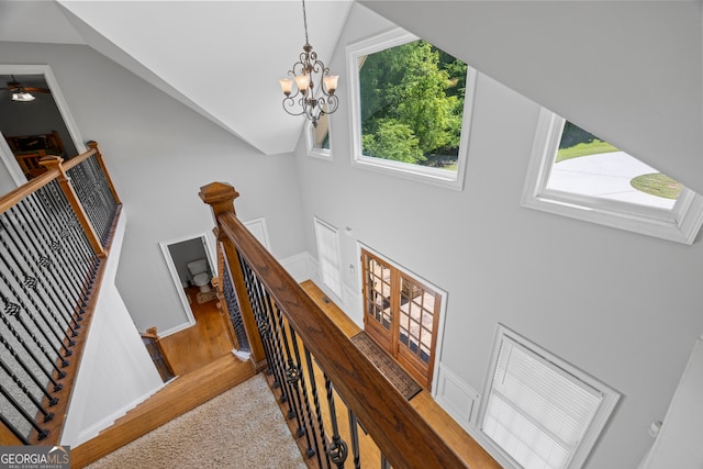 staircase featuring high vaulted ceiling, baseboards, and a chandelier