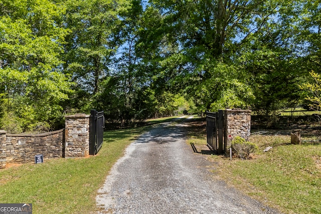 view of street featuring gravel driveway and a gated entry