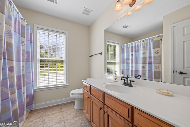 bathroom with baseboards, toilet, vanity, and visible vents