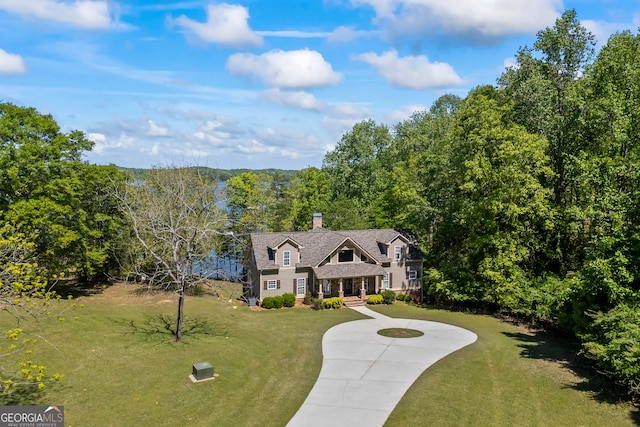 view of front of property featuring curved driveway, a chimney, and a front yard