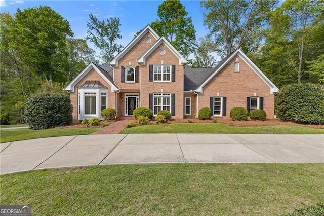 view of front facade with brick siding and a front yard