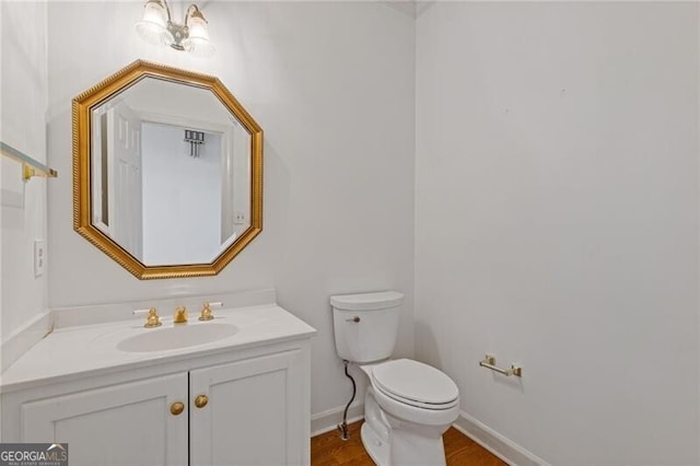 bathroom featuring toilet, vanity, wood finished floors, and baseboards
