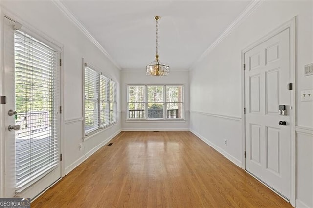 interior space featuring a chandelier, light wood finished floors, baseboards, and ornamental molding