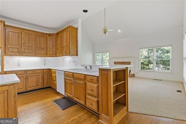 kitchen featuring a ceiling fan, a sink, dishwasher, light countertops, and a peninsula