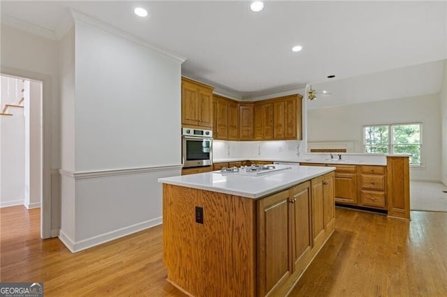 kitchen with light countertops, stainless steel oven, light wood finished floors, and white stovetop