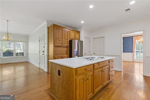 kitchen featuring stainless steel fridge, white gas cooktop, a chandelier, wood finished floors, and ornamental molding