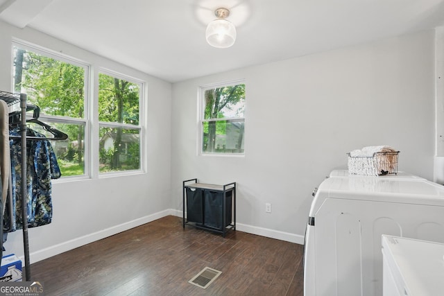 laundry room with laundry area, visible vents, washing machine and dryer, baseboards, and dark wood finished floors
