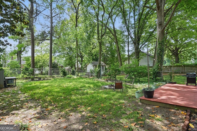 view of yard featuring a fenced backyard, a storage unit, an outdoor structure, and a deck