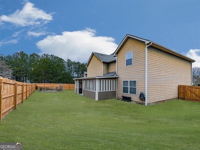 rear view of property with a fenced backyard, a sunroom, and a yard