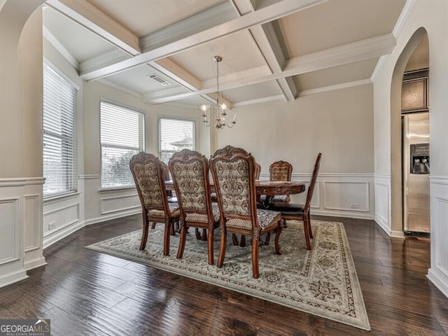 dining area featuring arched walkways, a chandelier, coffered ceiling, beamed ceiling, and a decorative wall