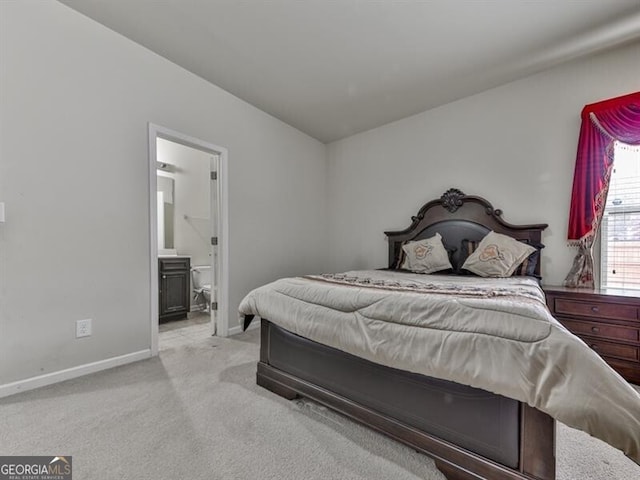 carpeted bedroom with connected bathroom and baseboards