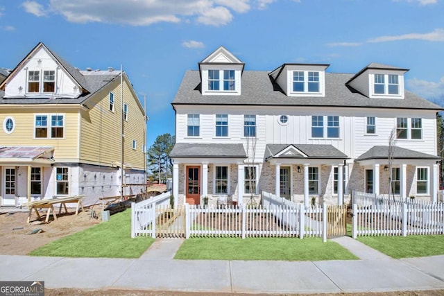 view of property with a gate, roof with shingles, a front lawn, and a fenced front yard