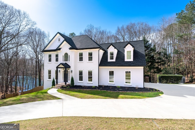 view of front facade featuring stucco siding, a shingled roof, a front lawn, and fence